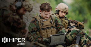 A soldier using a military-grade laptop in a combat zone - including the HIPER Global logo