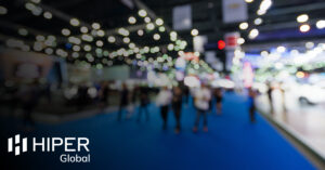 A blurred shot of people walking through a trade show - including the HIPER Global logo
